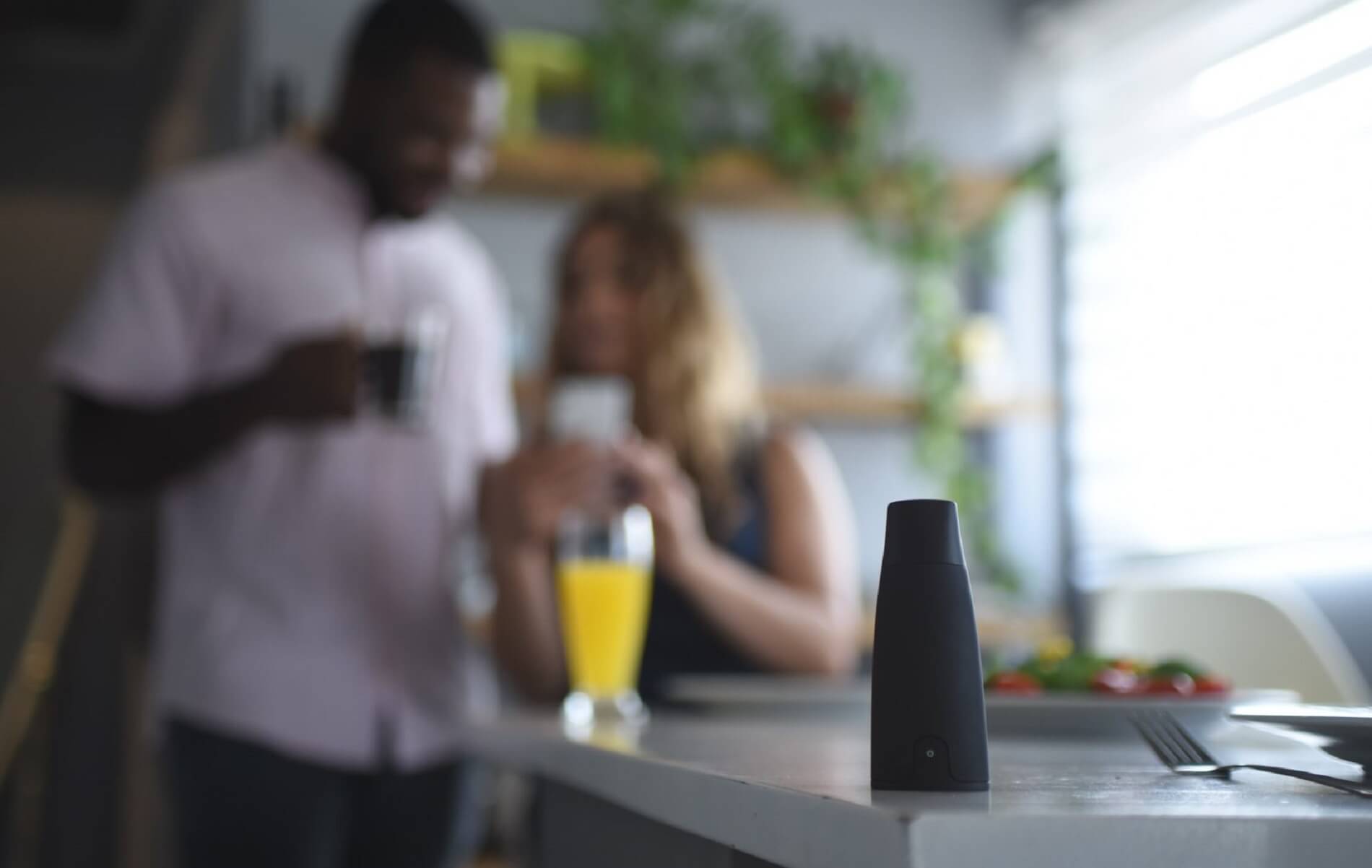 Lumen's device on a dining table, a man and a woman behind it